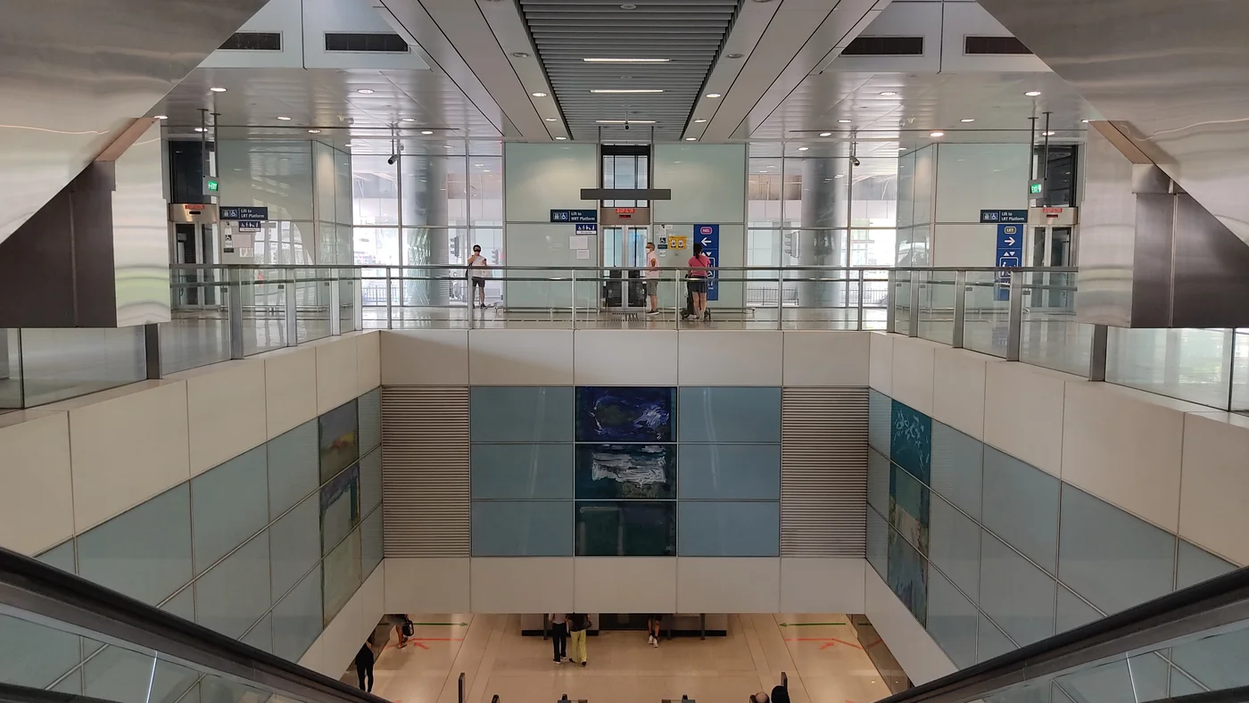 Blue and green glass artwork panels on the walls inside Punggol MRT station, beneath the concourse.